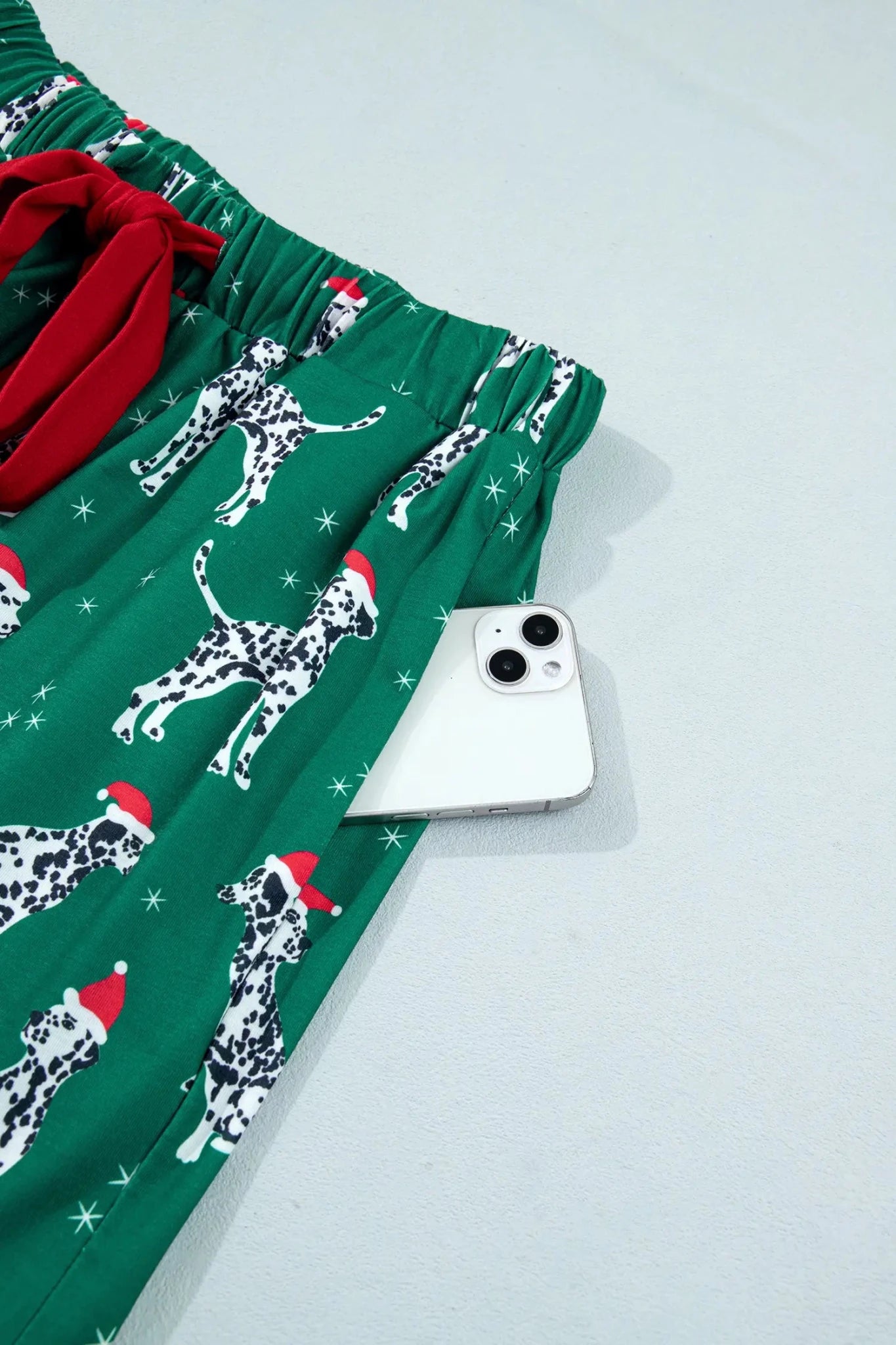 Green Dalmatian holiday pants with Santa hats and a phone in pocket.