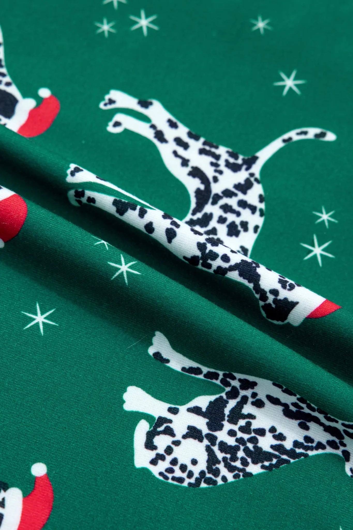 Green fabric with Dalmatian dogs in Santa hats and white stars.