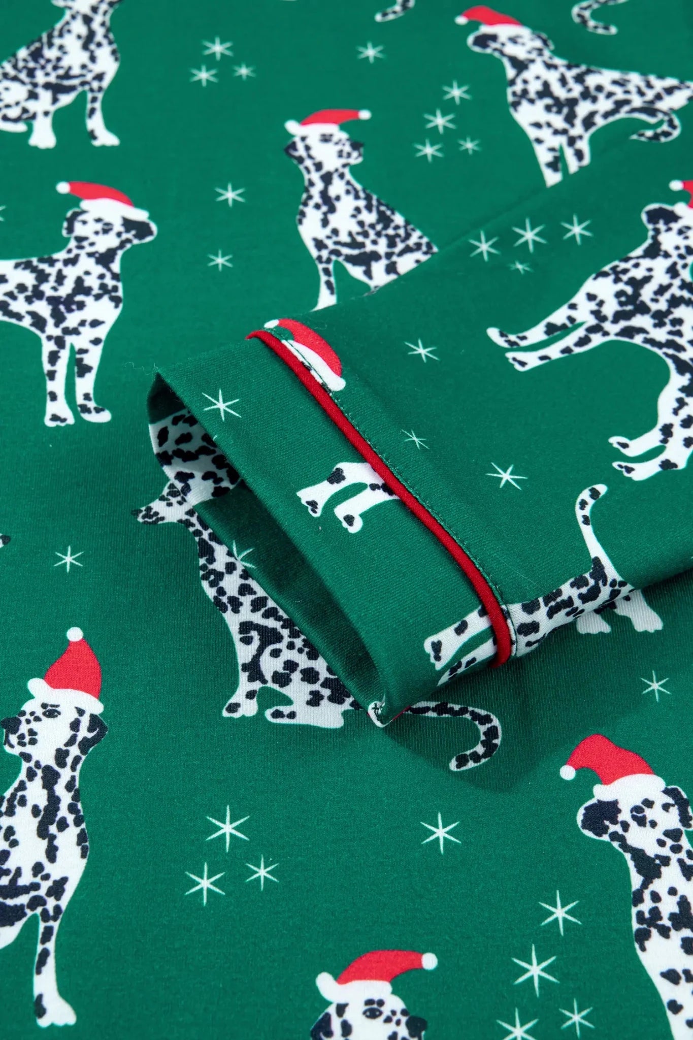 Folded green fabric with Dalmatian dogs, Santa hats, and white stars.