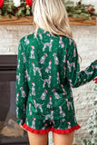 Woman in green Dalmatian-print pajamas with red ruffle trim, standing by a fireplace.