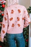 Back view of person in pink gingerbread-print sweater and blue jeans by Christmas tree.