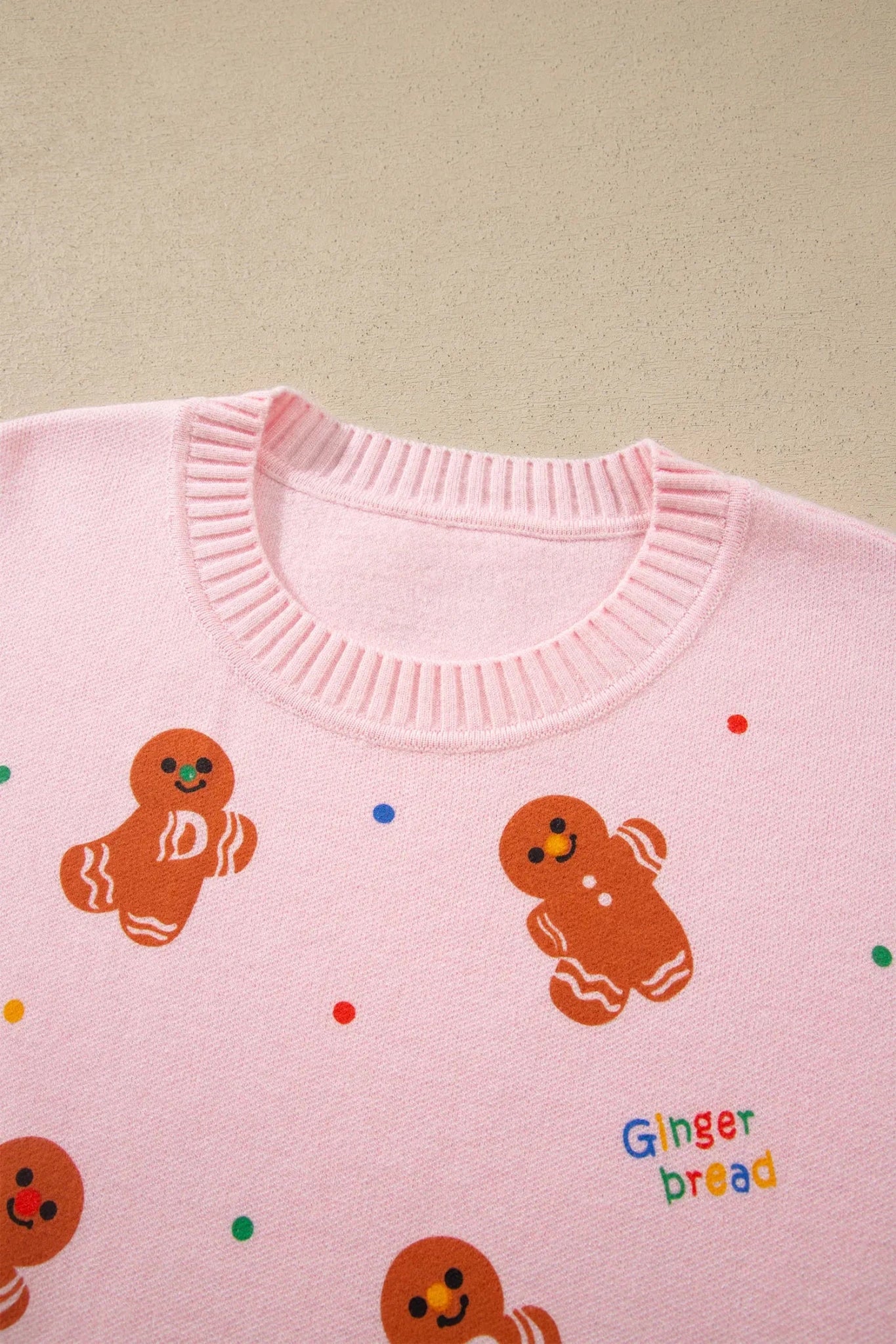 Close-up of pink sweater with gingerbread print and colorful “Ginger bread” lettering.