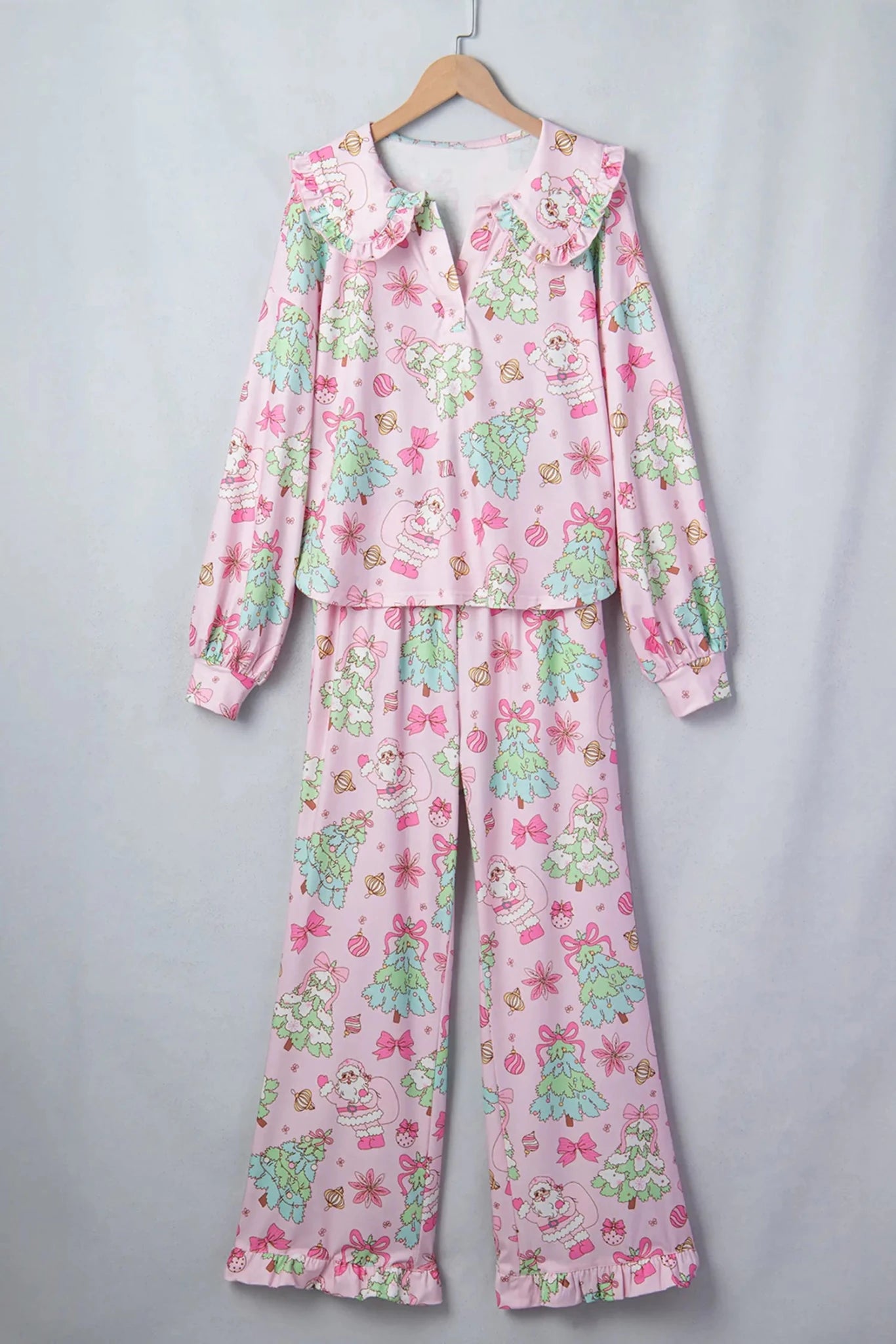 Light pink pajama set with colorful cartoon print on wooden hanger.