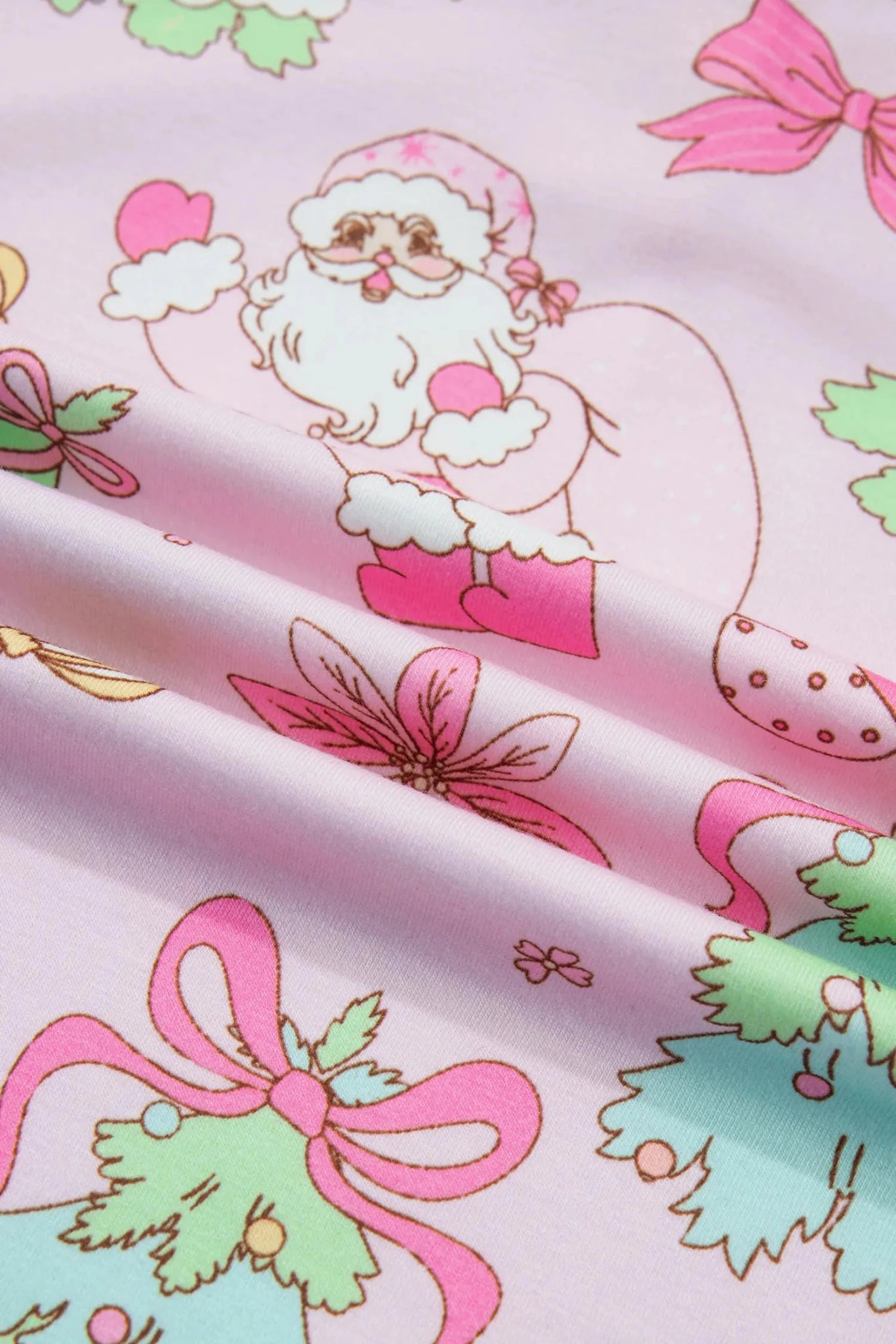 Close-up of light pink fabric with Santa and festive holiday print.
