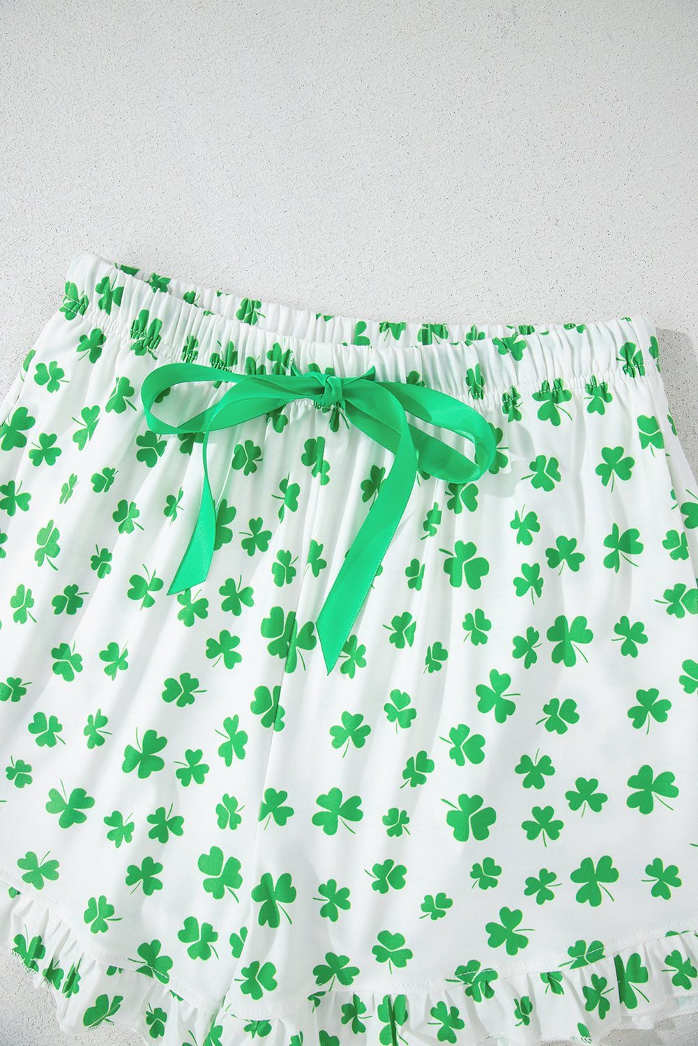 Green shamrock-patterned shorts with a green ribbon on a white background