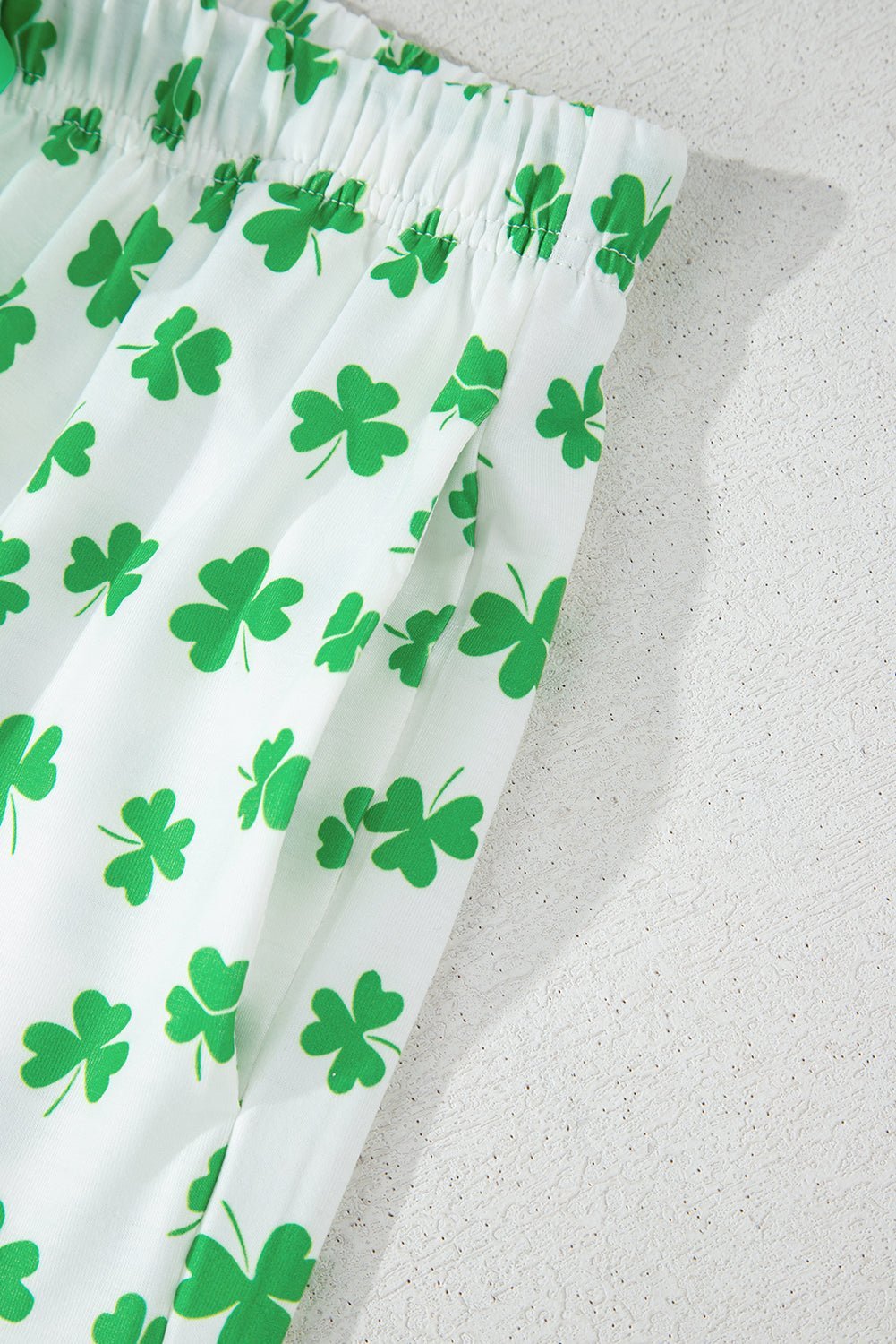 White fabric with green shamrock pattern on a light gray background