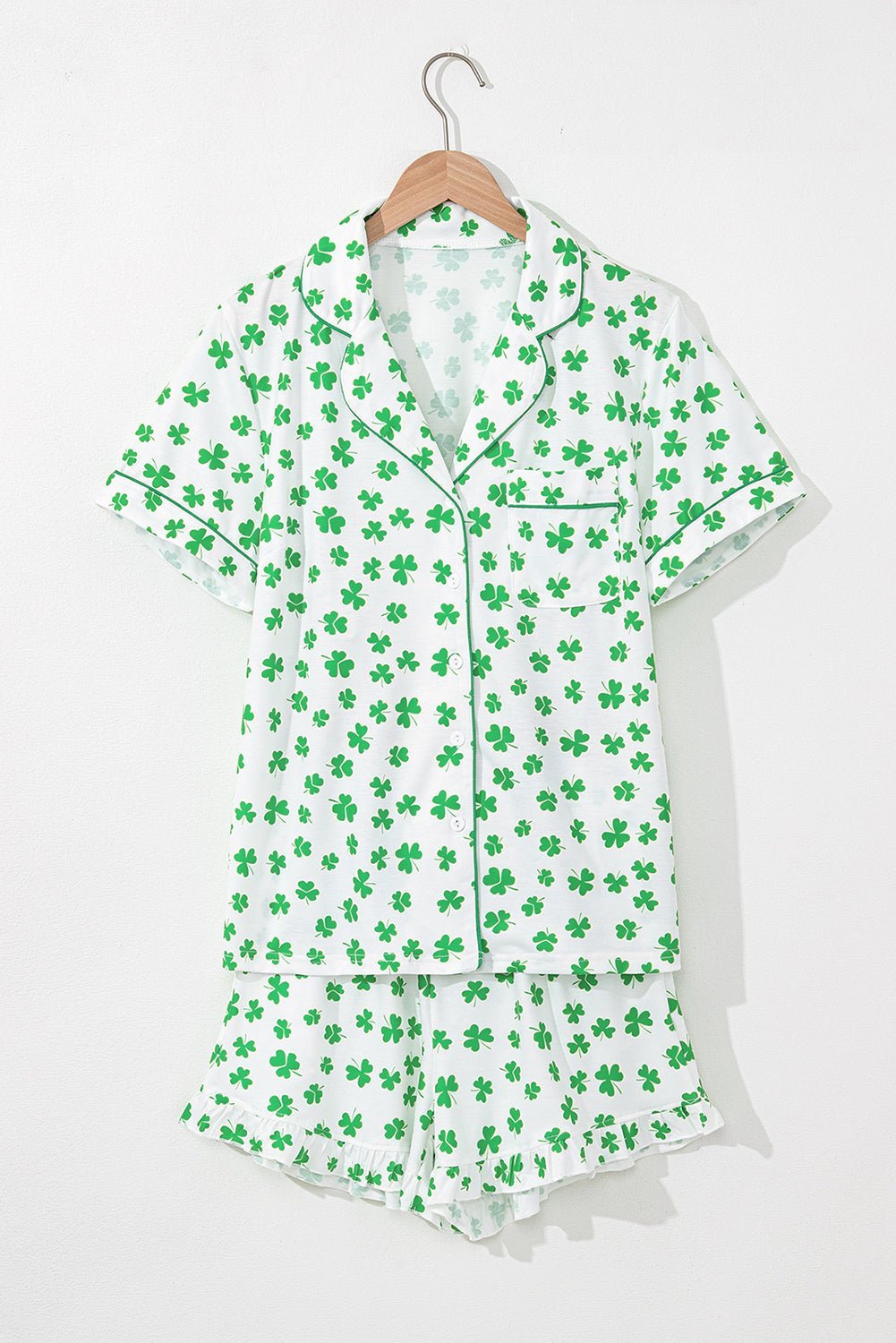 Green shamrock patterned pajama set on a hanger against a white background