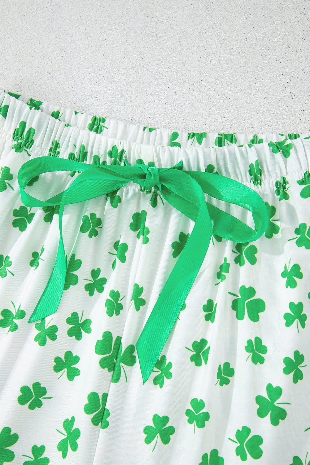 White fabric with green shamrock pattern and a green ribbon on a white background