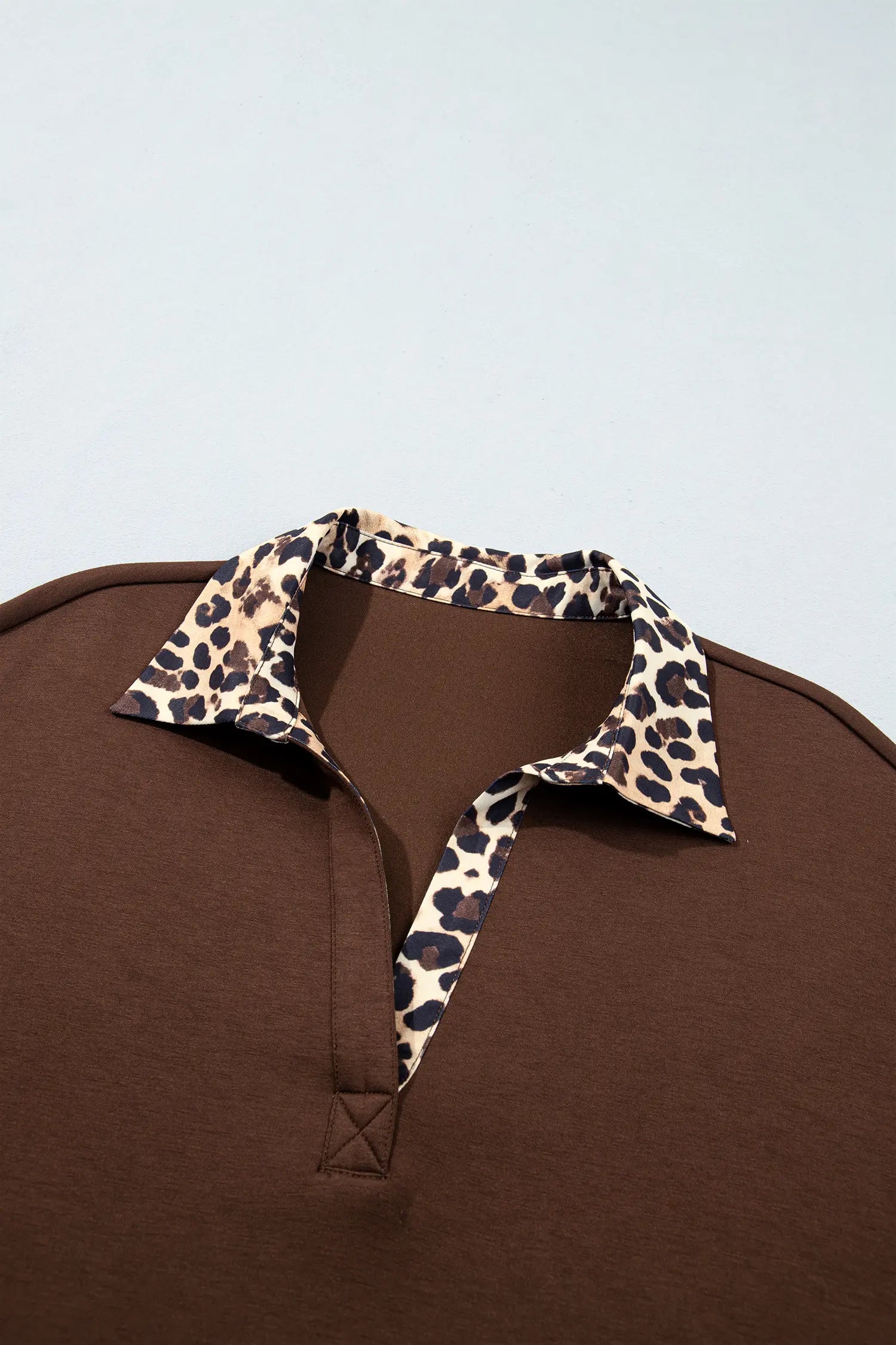 Close-up of leopard print collar and cross stitch V neck on coffee dress