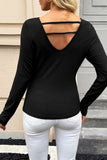 Back view of woman in black cutout-back top and white pants outdoors.