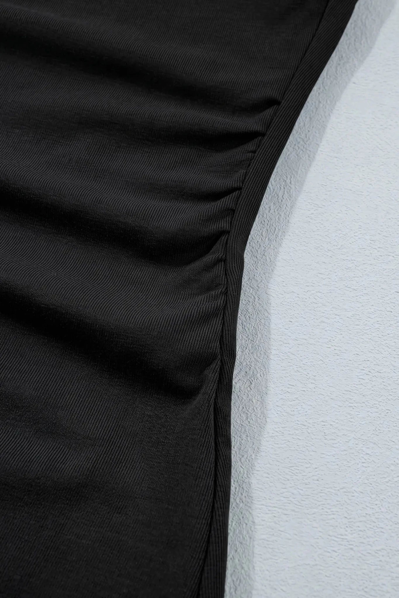 Close-up of black ribbed fabric with gathered seam and textured surface
