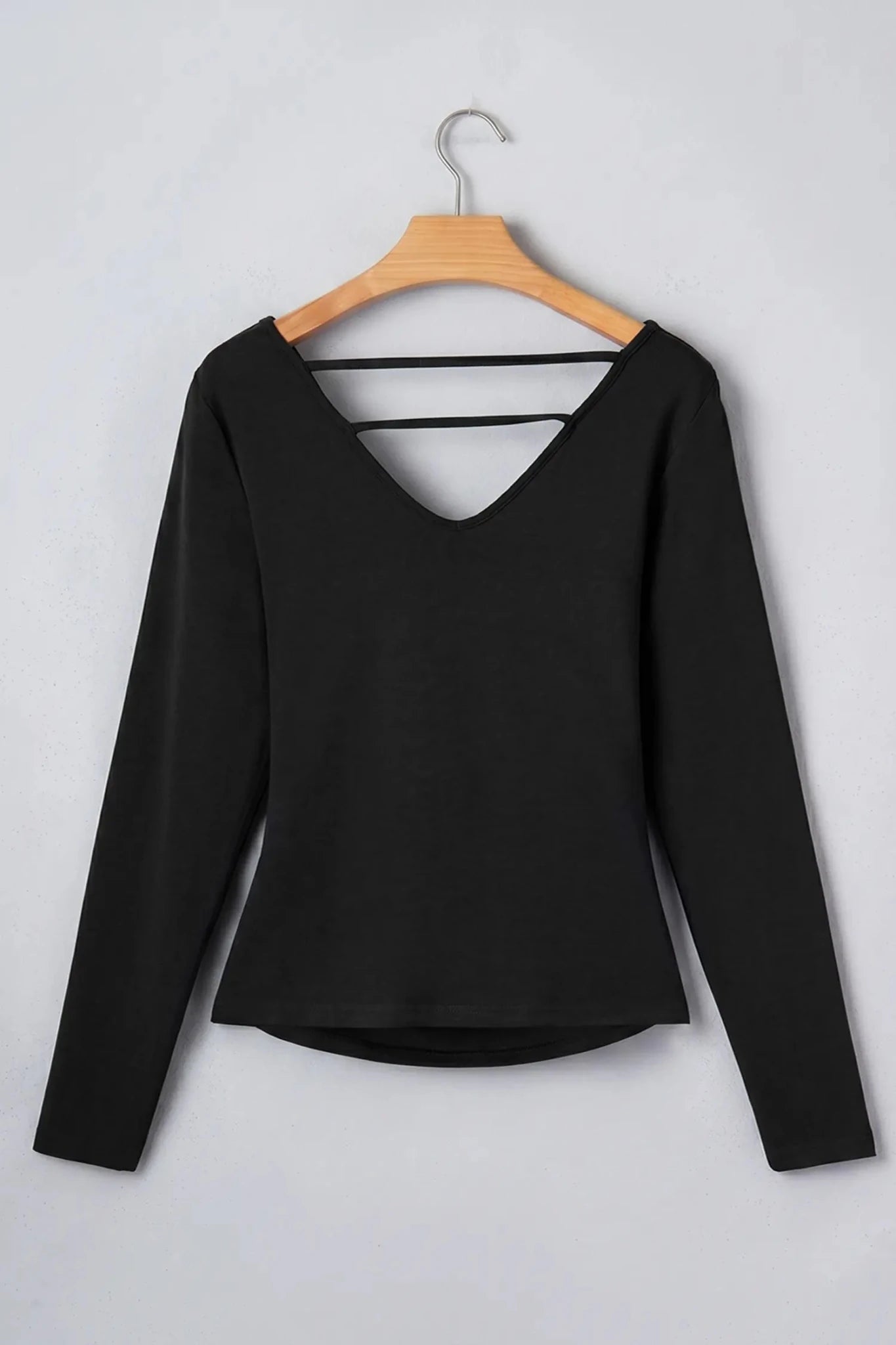 Black V-neck crop top with double back cutout straps on wooden hanger.