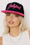 Woman wearing a black cap with pink 'Godspeed' text on a white background