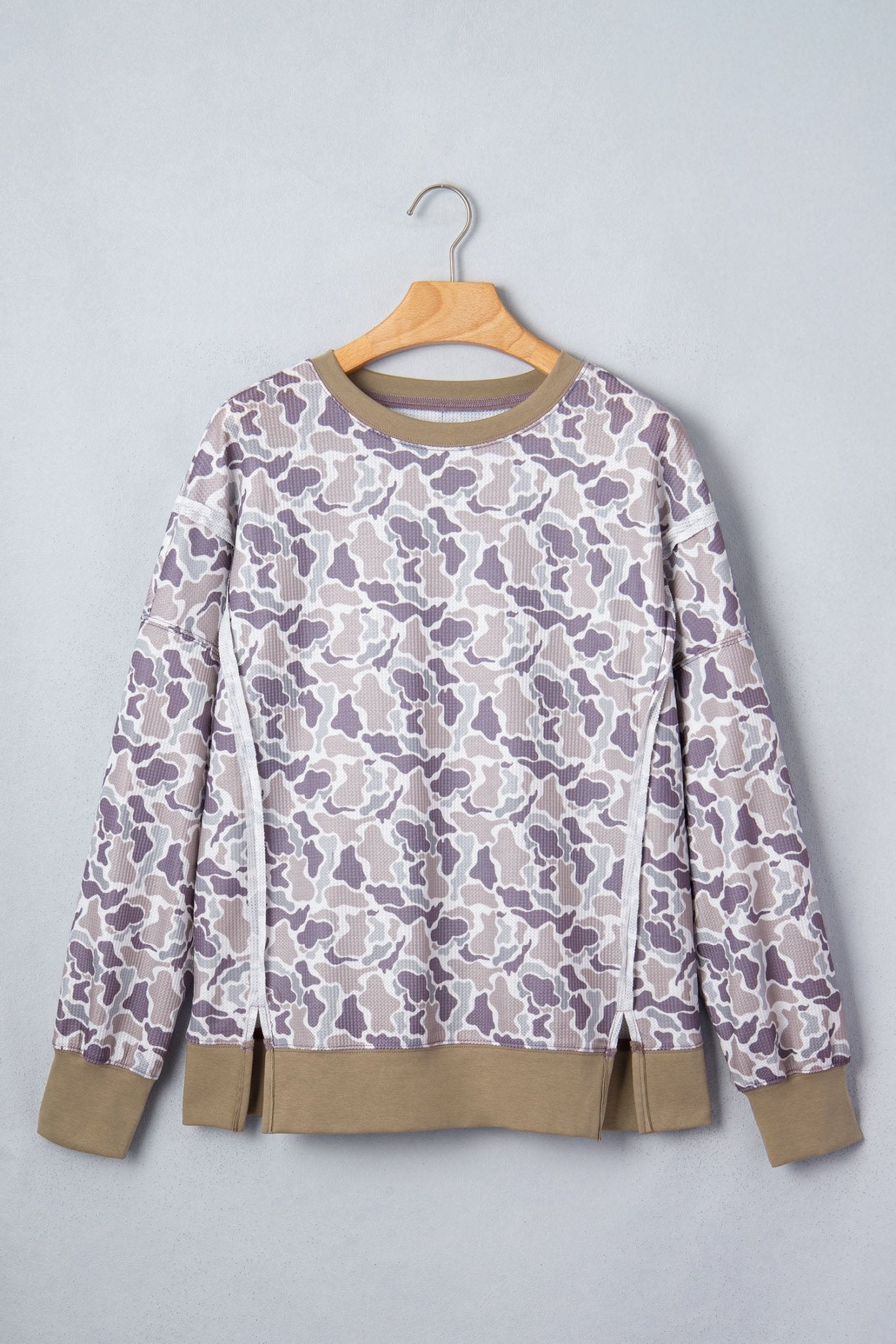 Beige-gray-purple camouflage sweatshirt with tan ribbed cuffs and hem on hanger.