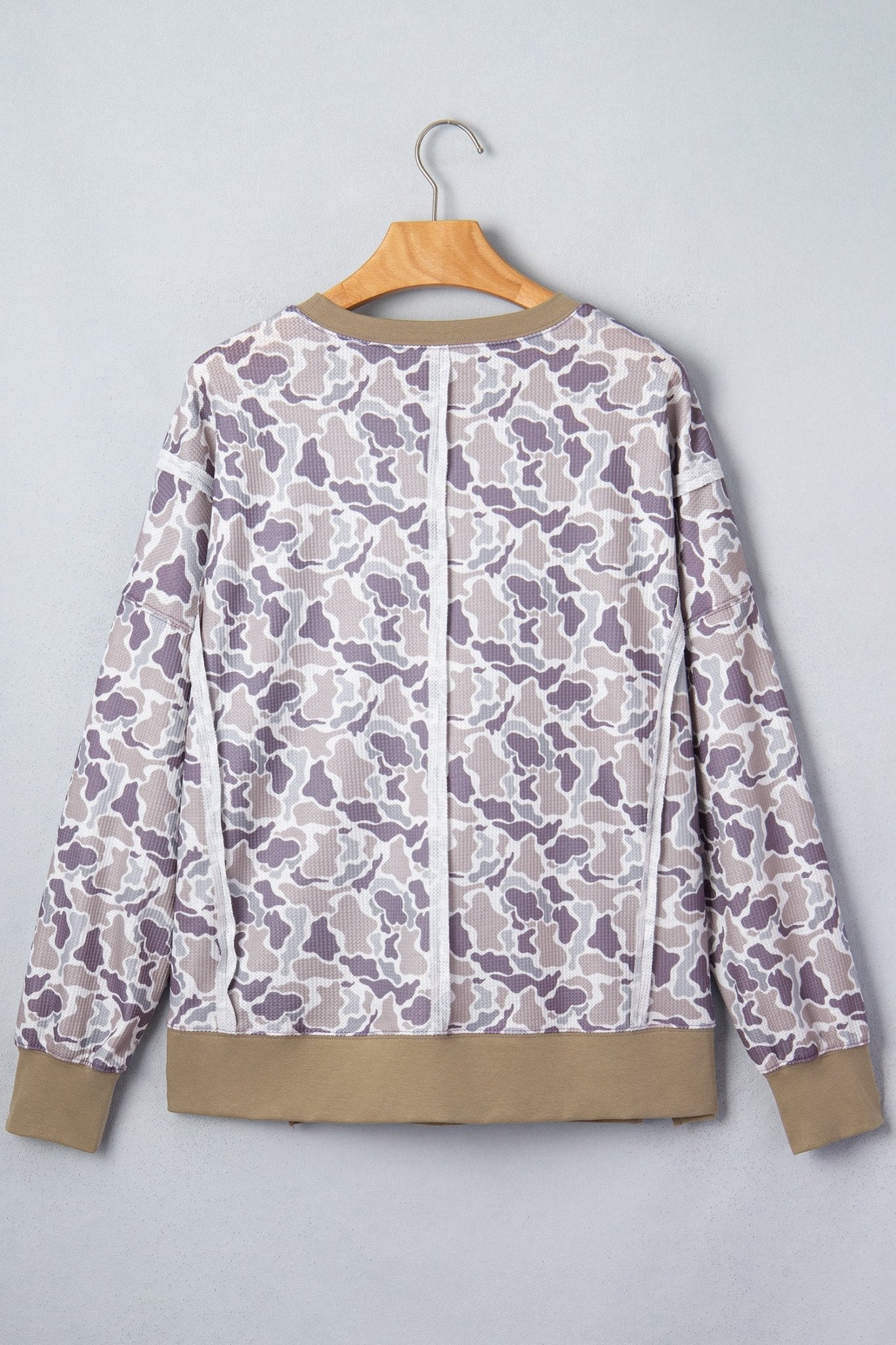 Beige-white-purple camo zip-up jacket with tan ribbed cuffs and hem on hanger.
