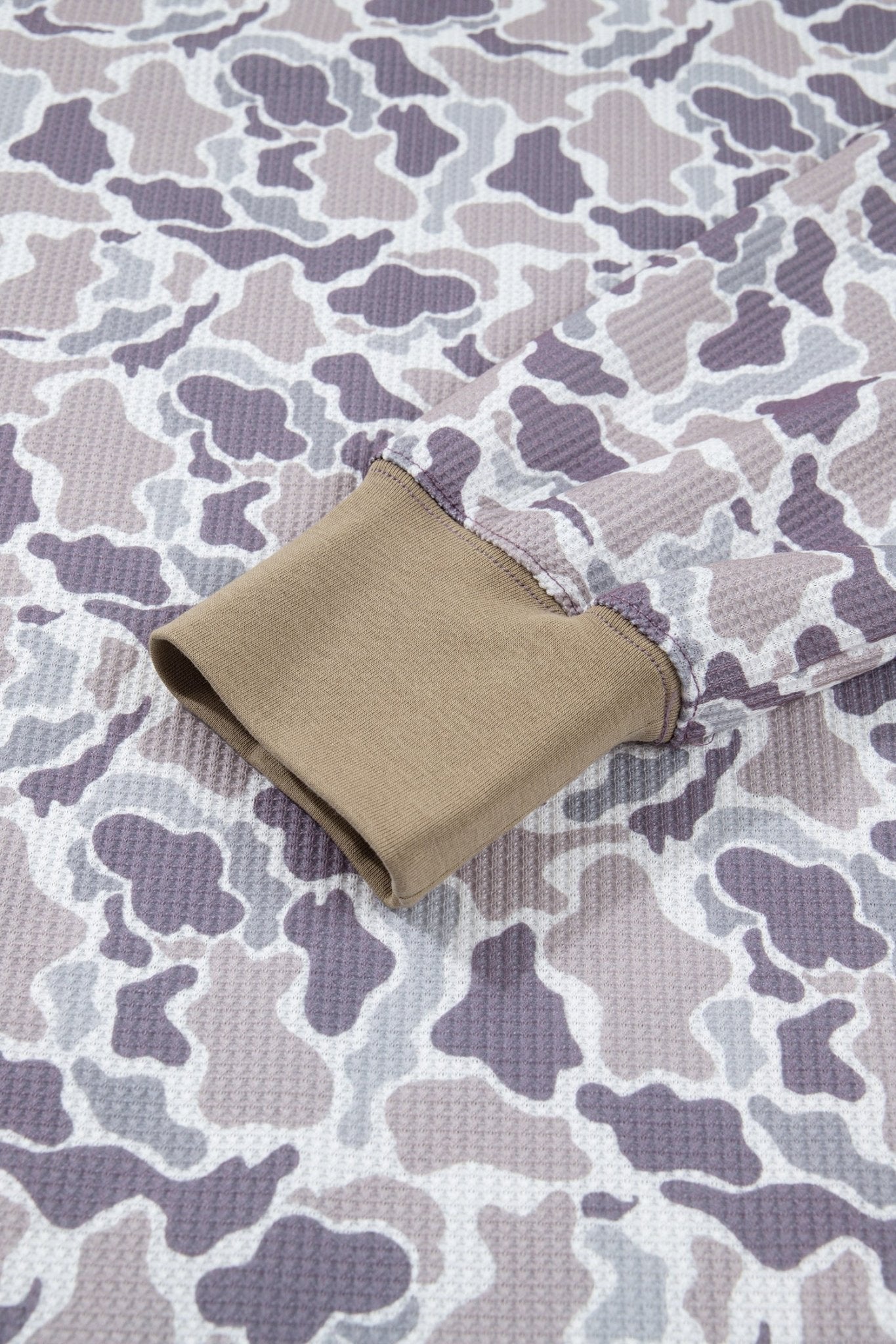Close-up of a camouflage-patterned fabric sleeve with a tan cuff, showing the textured waffle-weave material.