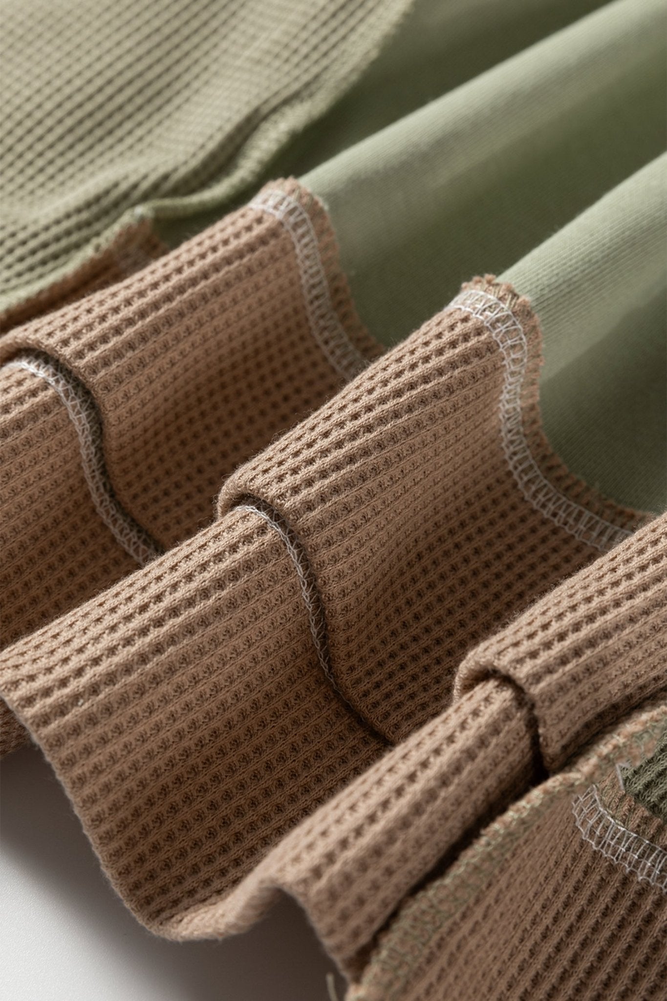 Close-up of brown gloves with textured palm and fingers on a light green background
