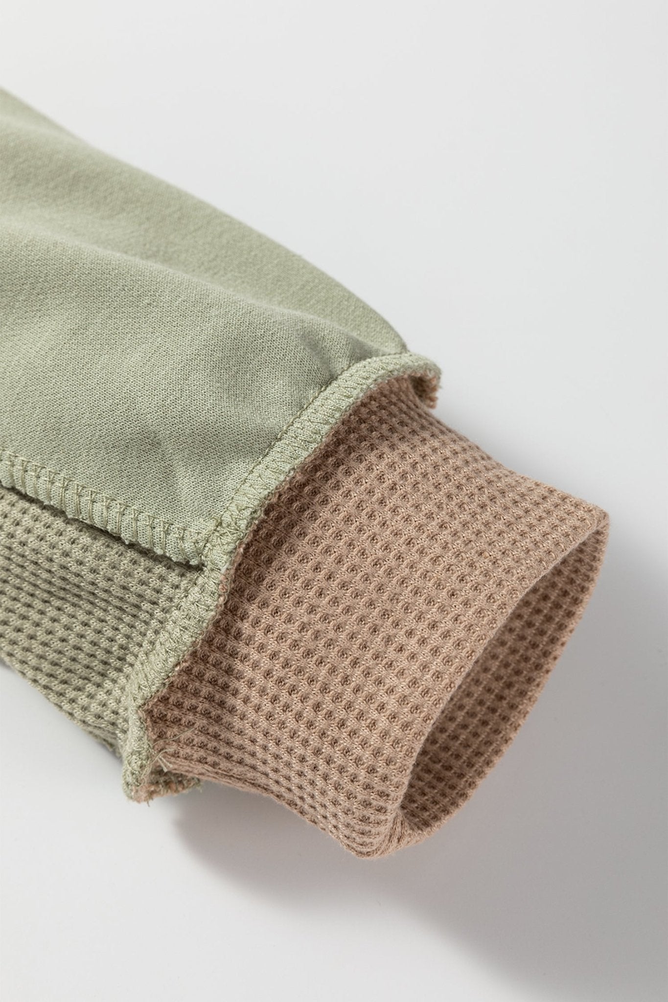 Close-up of a green and brown textured sleeve on a light gray background