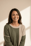 Woman wearing a green and beige sweater with a neutral background