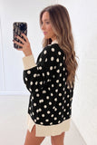 Woman in black knit sweater with cream polka dots and ribbed trim.