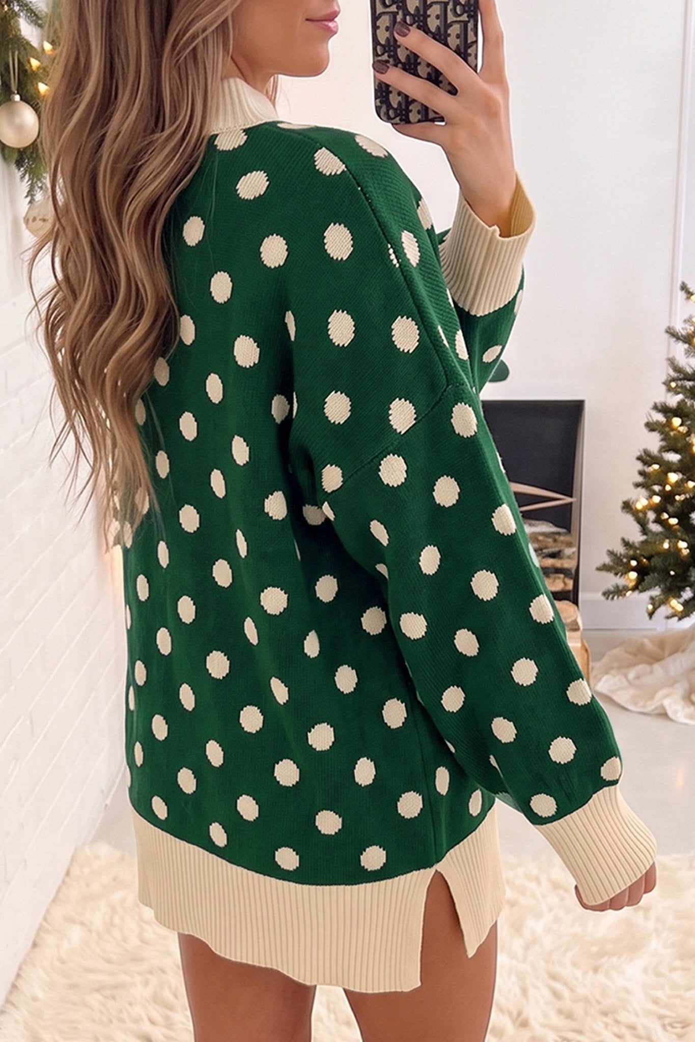 Woman in oversized green sweater with cream polka dots and ribbed trim.