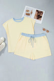 Yellow pajama set with blue accents on a gray surface, accompanied by sunglasses and a magazine.