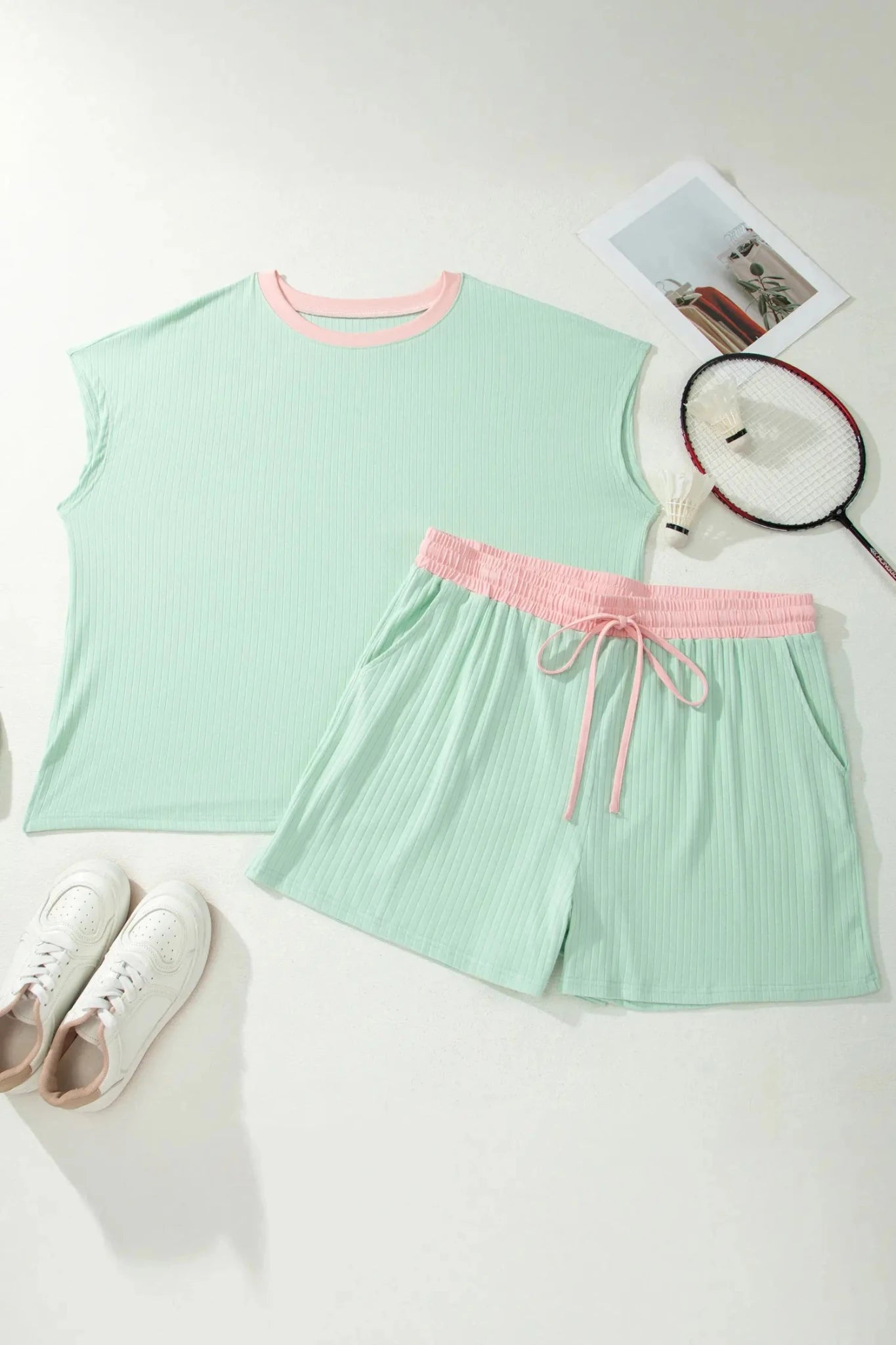 Light green sleeveless top and shorts with pink accents on a white surface.
