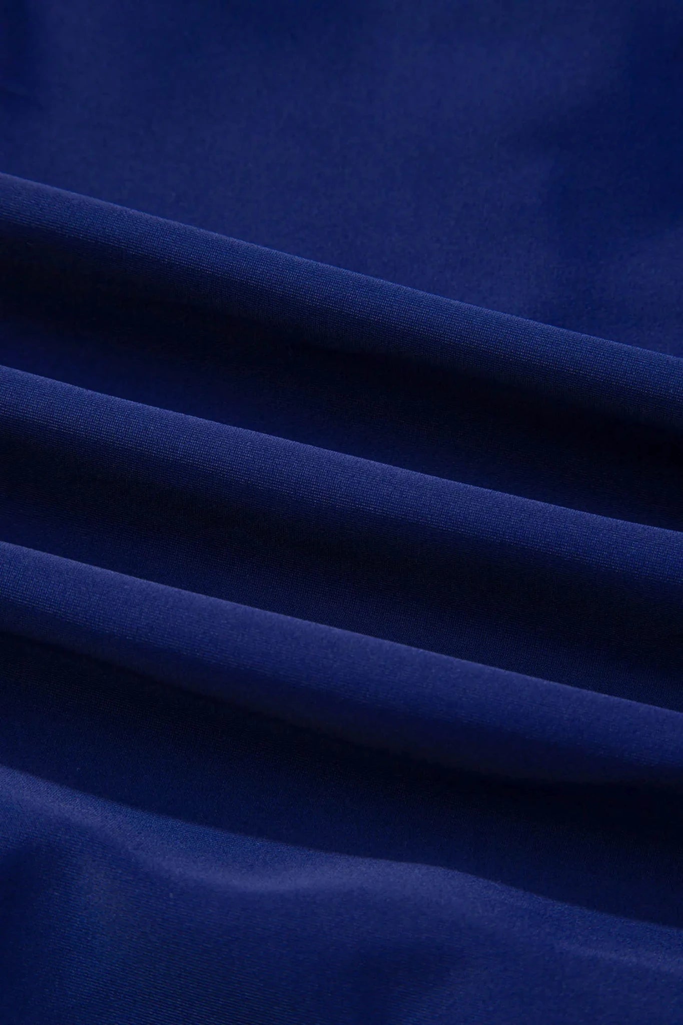 A close-up of draped royal blue fabric with soft folds and a smooth texture.
