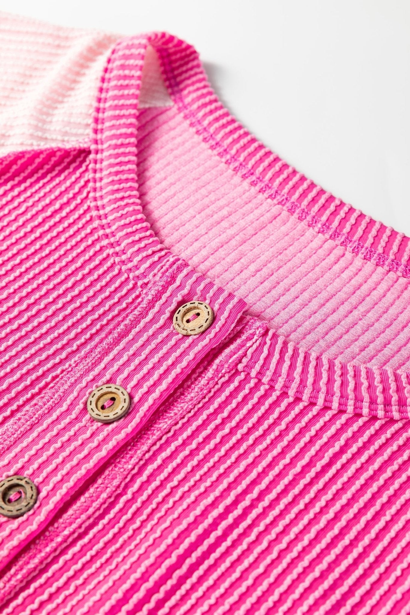 Close-up of a pink baby outfit with buttons on a white background