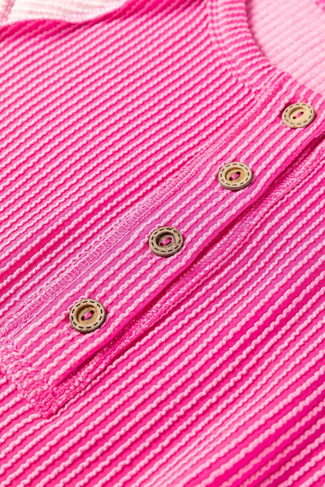Close-up of a pink textured fabric with gold buttons