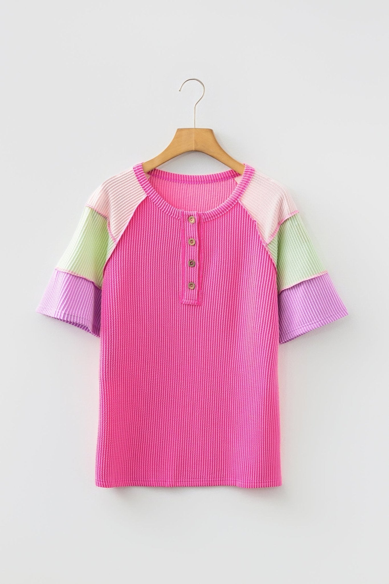 Color-blocked dress with pink, green, and purple sleeves on a hanger against a white background