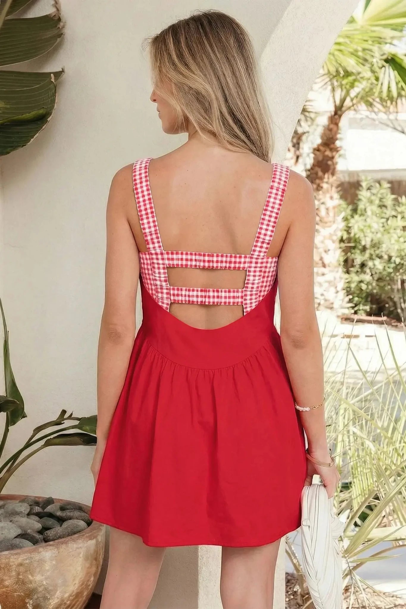 Woman wearing a red dress with a checkered back in an outdoor setting