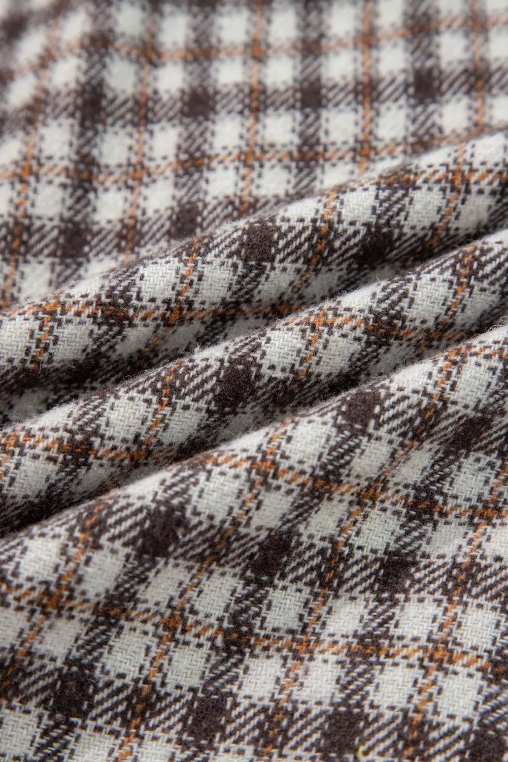 Close-up of plaid fabric with brown, white, and orange colors.