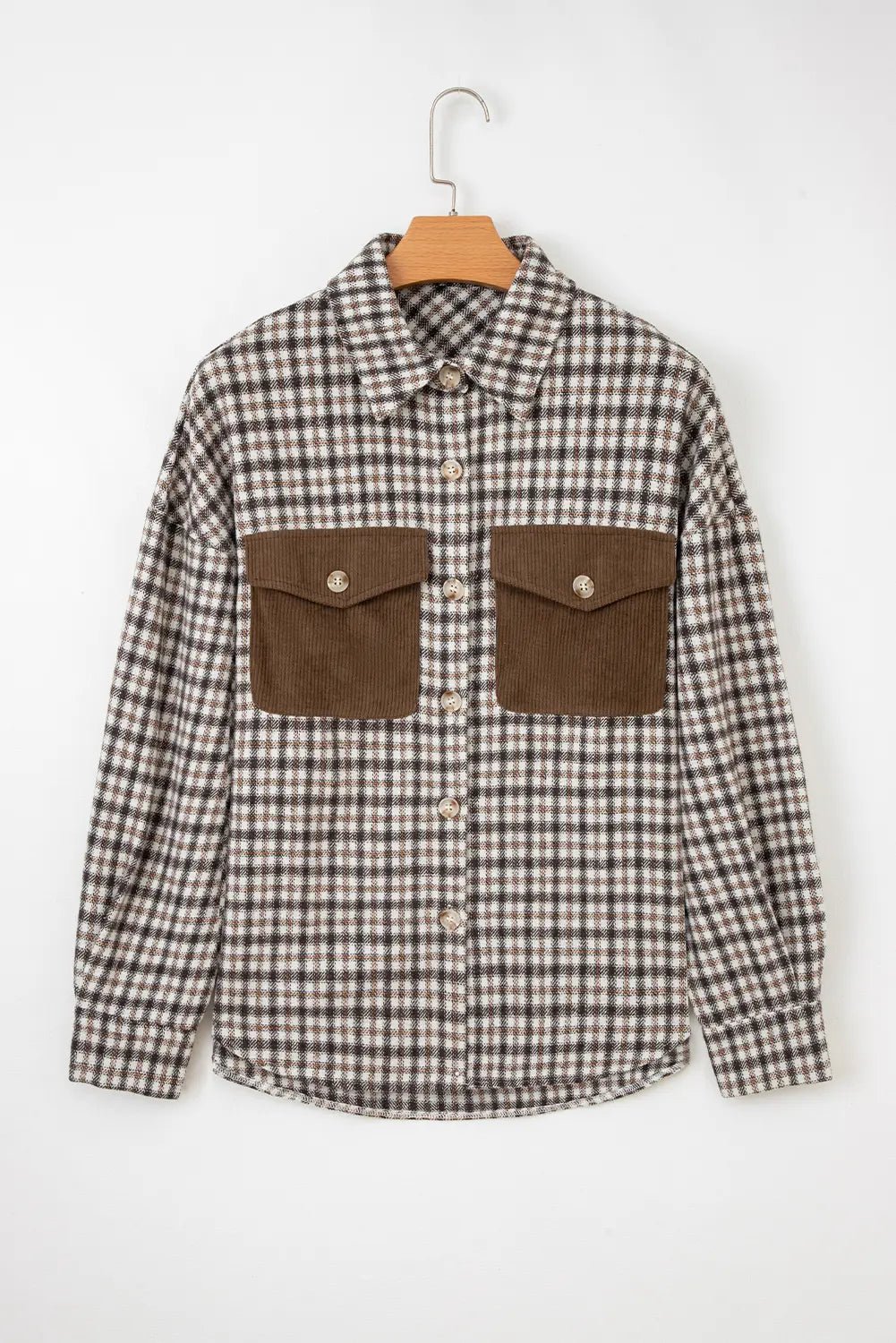 Plaid shirt with brown pocket flaps on a hanger against a white background