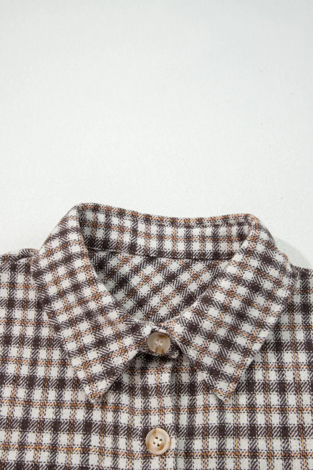 Close-up of a checkered shirt collar with buttons on a white background