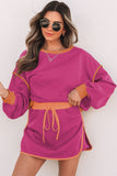 Woman wearing a pink dress with orange accents against a white background