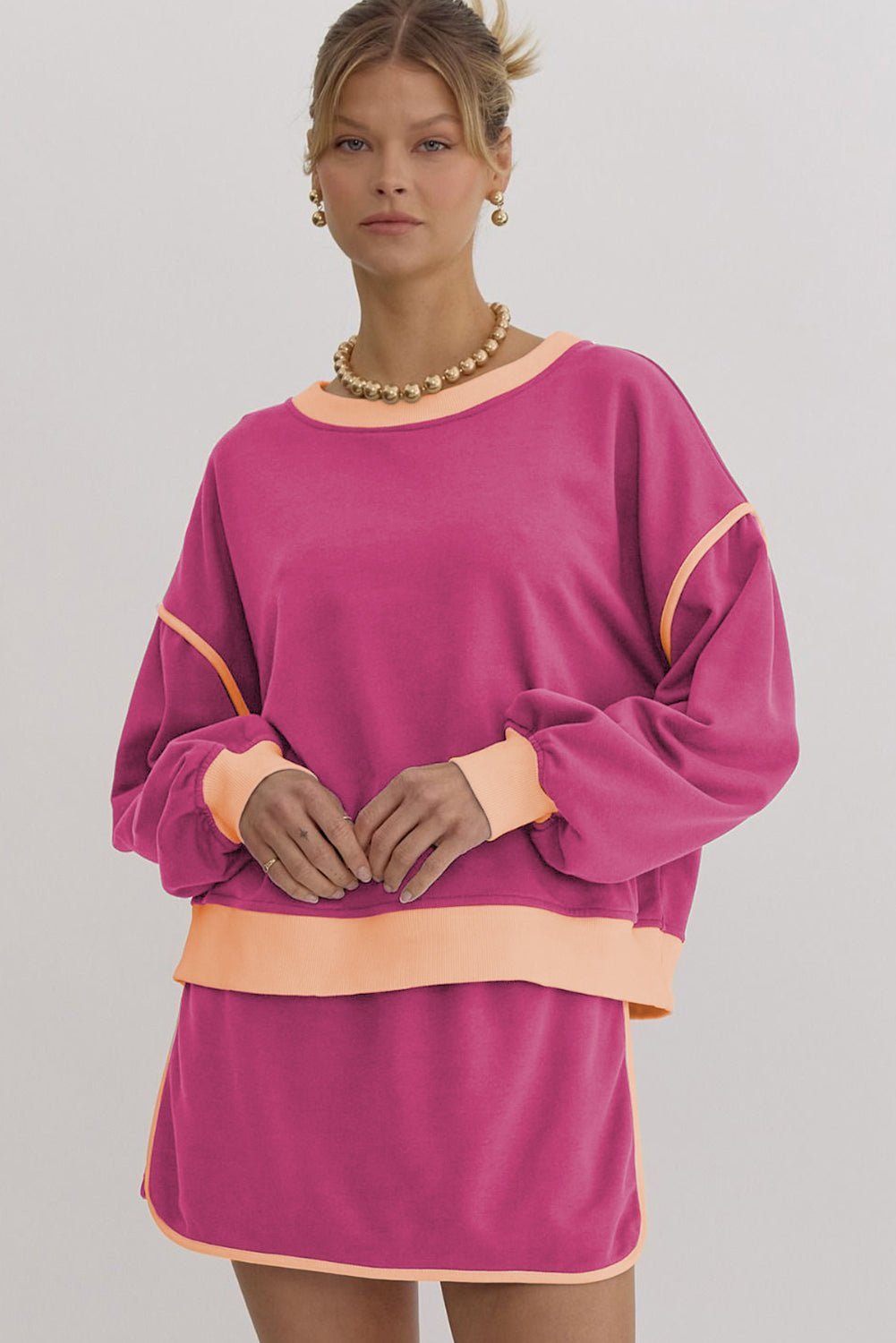 Woman wearing a pink dress with orange accents on a gray background