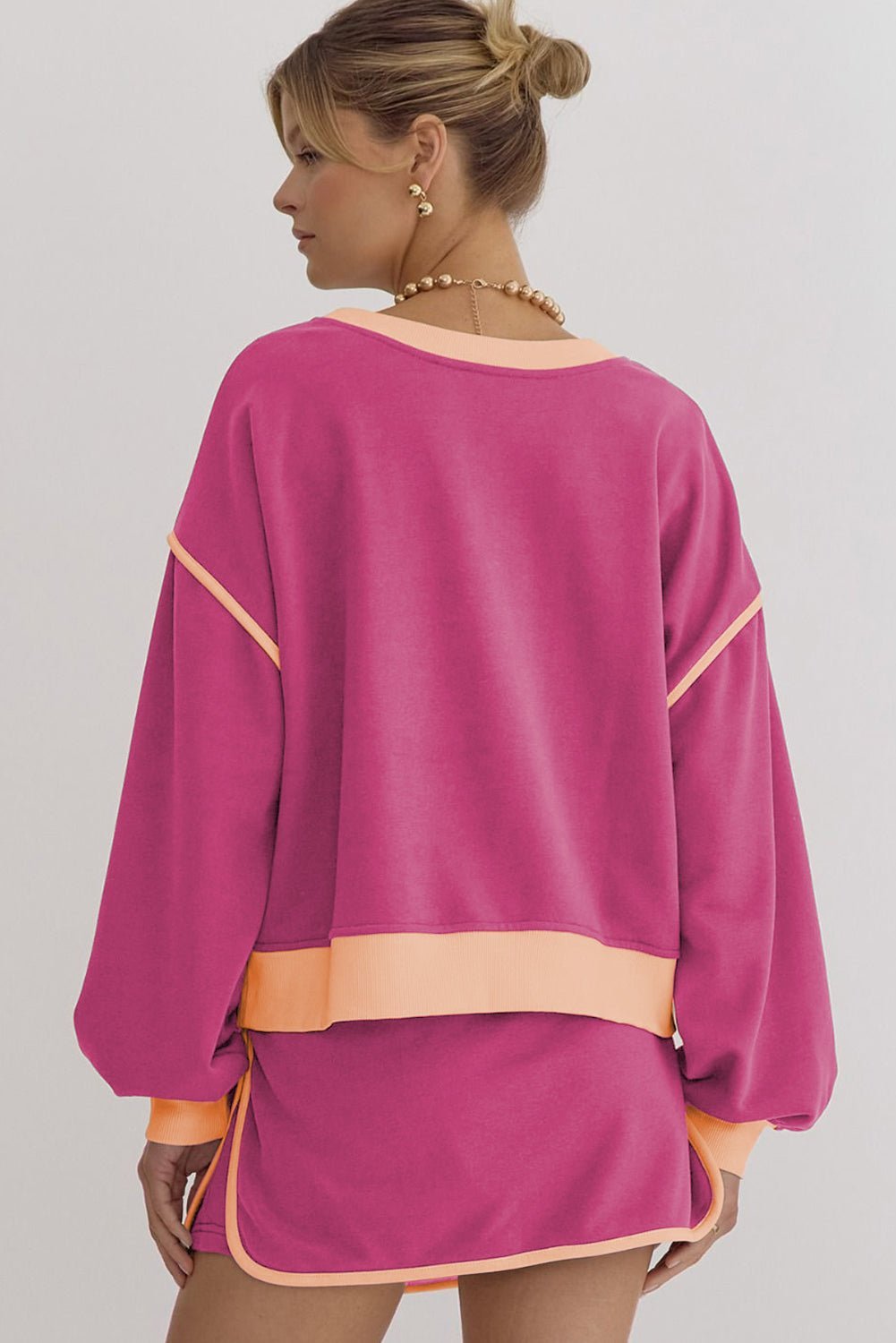 Woman wearing a magenta dress with peach accents on a gray background