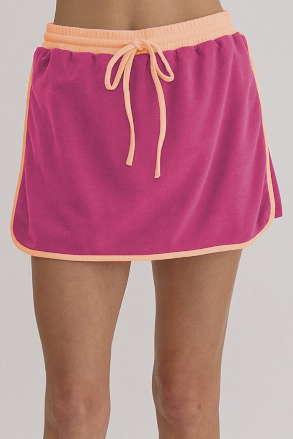 Pink skirt with peach trim on a plain background