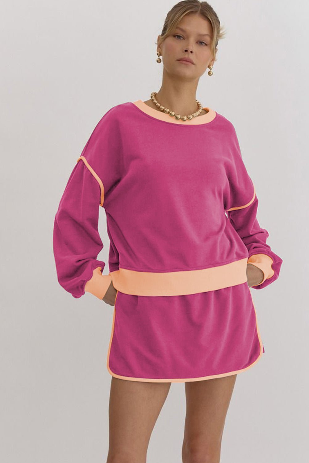 Woman wearing a pink dress with a belt on a plain background