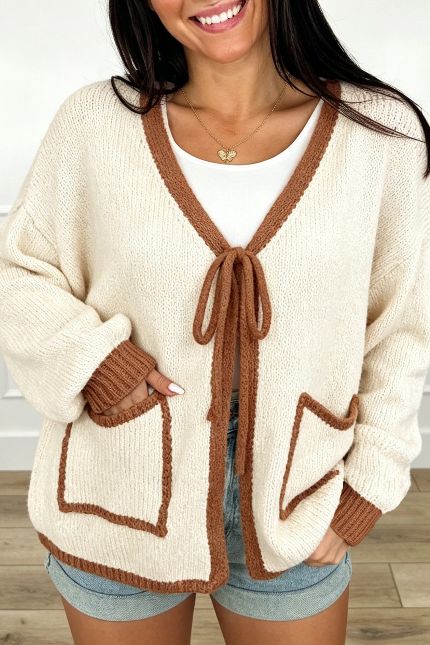 Woman in apricot knit cardigan with chestnut trim, tie front and patch pockets, front view