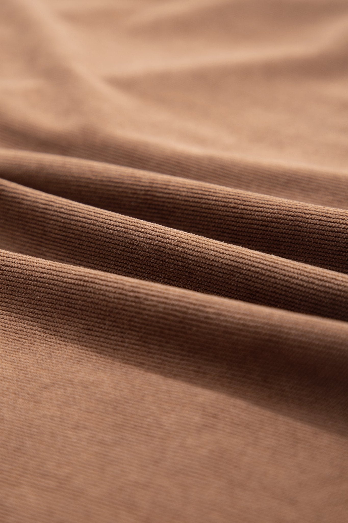 A close-up of draped brown ribbed fabric, showing the texture and folds of the material.