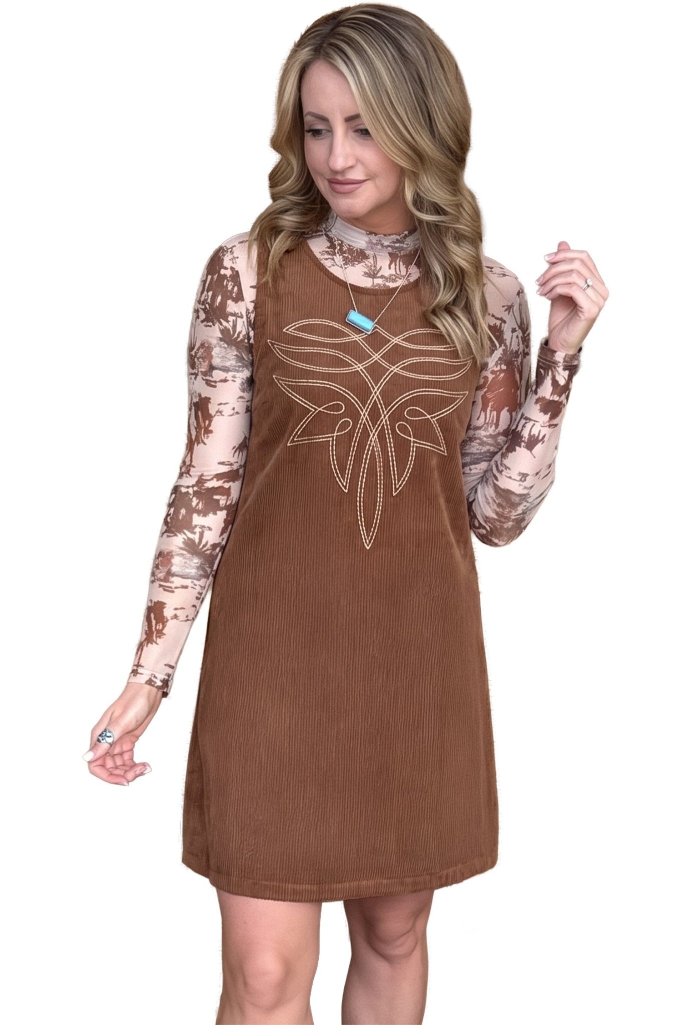Woman in brown corduroy dress over brown-beige camouflage top with white chest design.