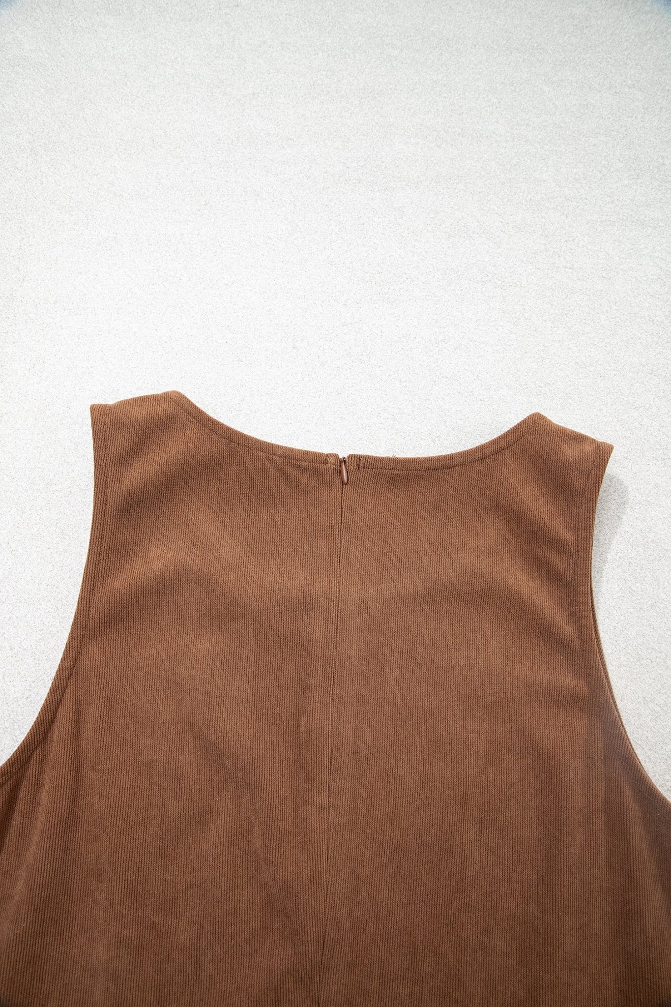 Close-up back of brown sleeveless top with round neckline and center zipper.