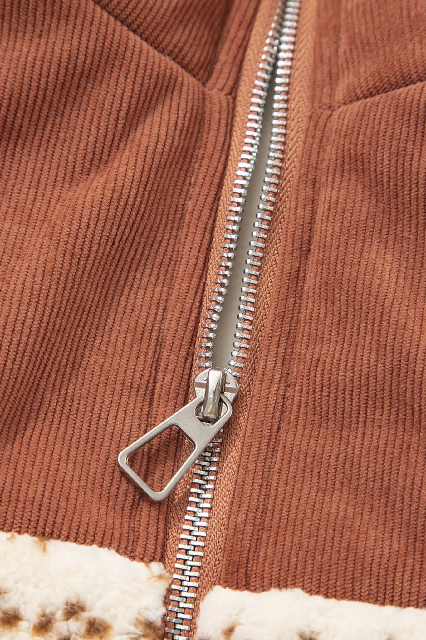 Close-up of brown corduroy jacket with silver zipper and white sherpa lining.