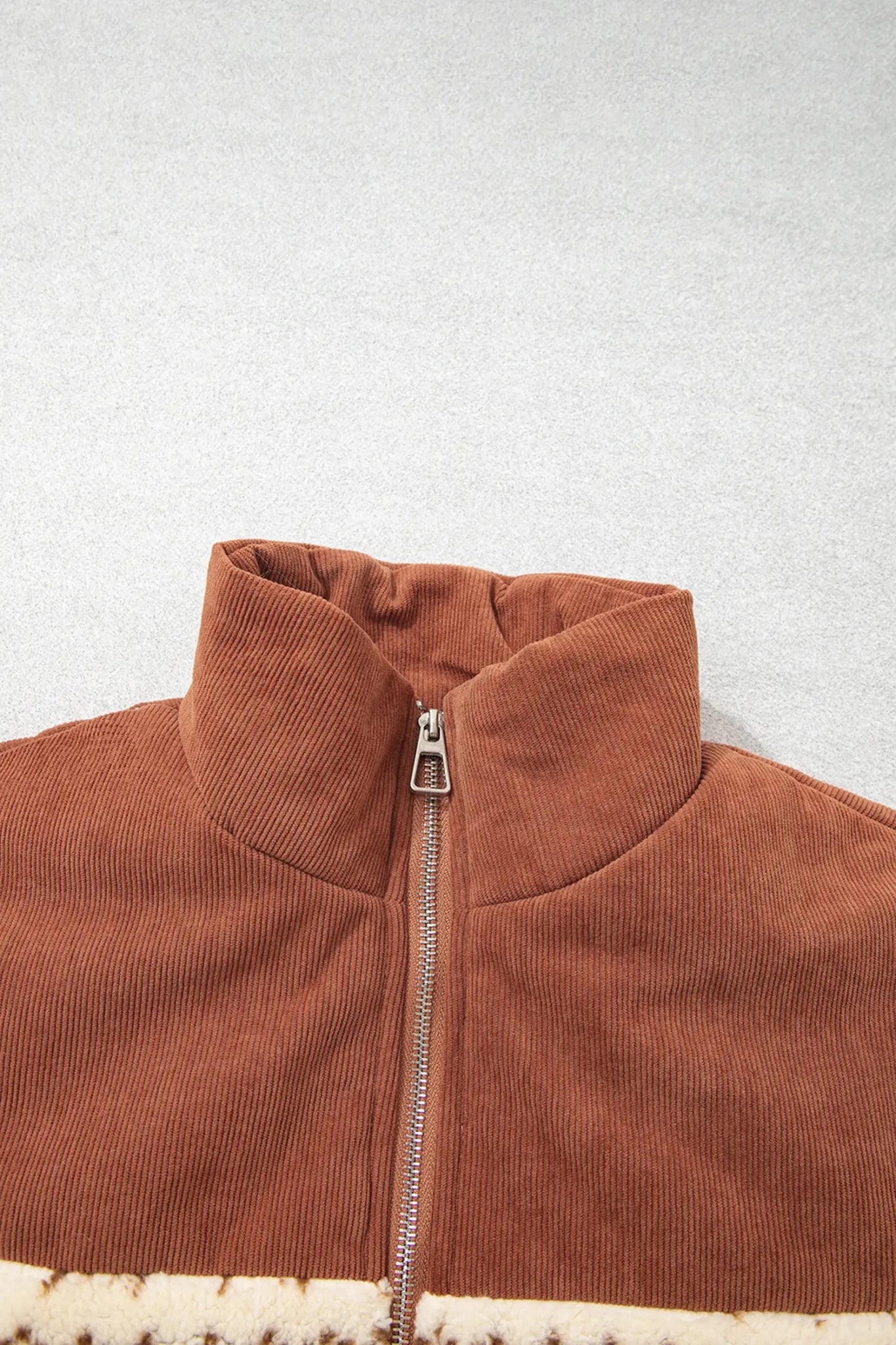 Close-up of brown corduroy jacket with high collar and cream sherpa lining.