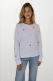 Woman wearing a light gray sweater with star patterns on a white background