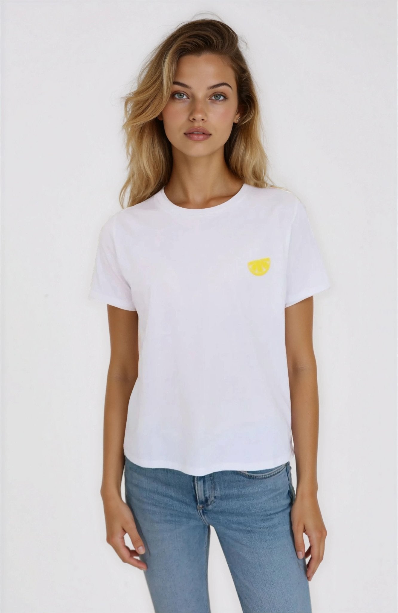 Woman wearing a white t-shirt with a yellow heart design on a plain background