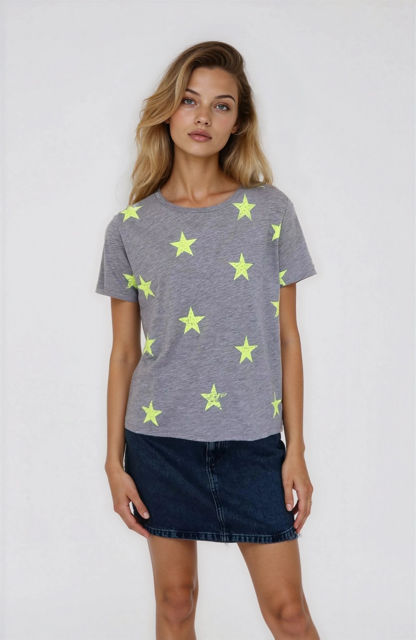 Woman wearing a gray t-shirt with yellow star patterns on a plain background