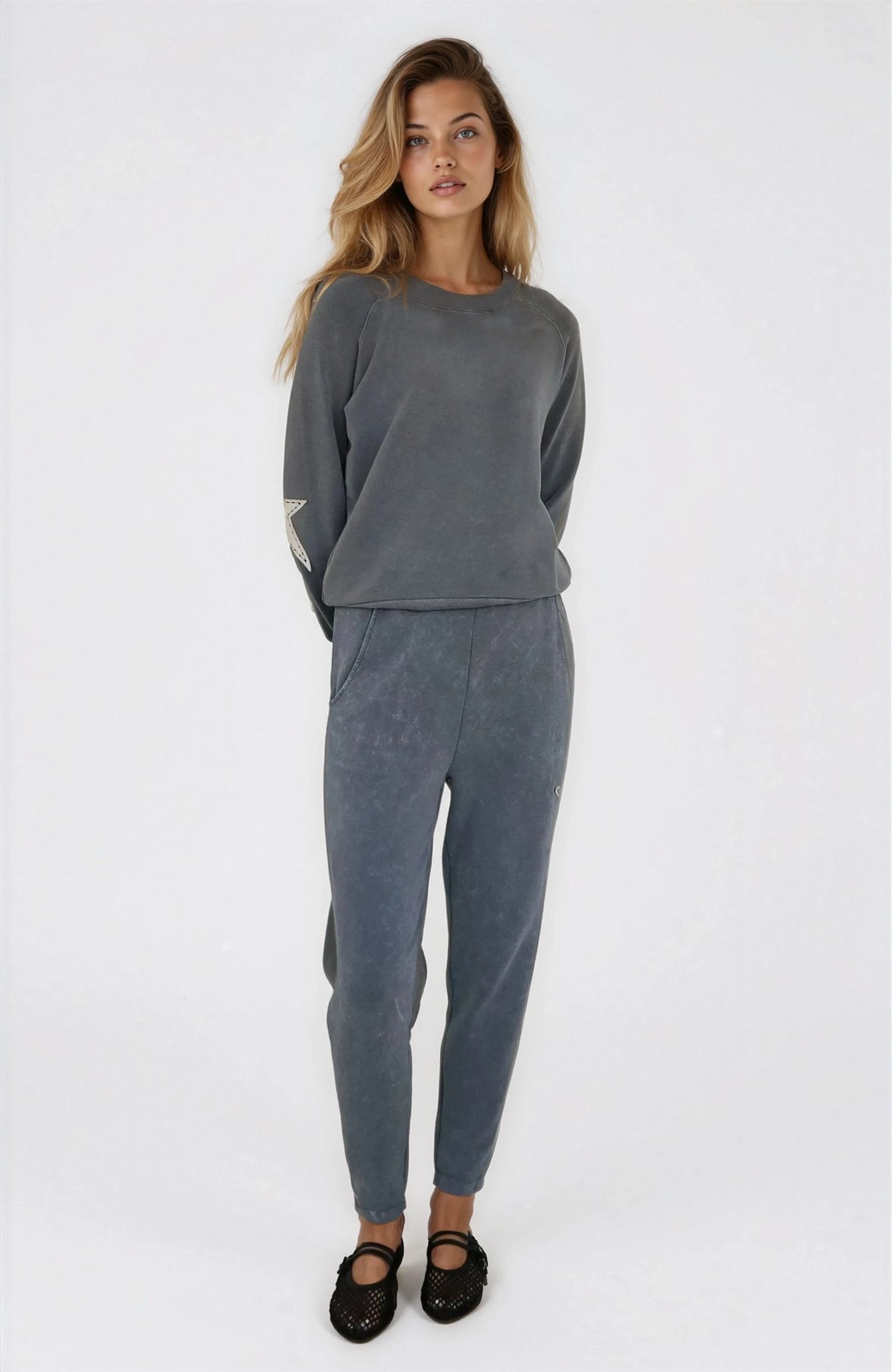 Woman wearing a gray sweatshirt and pants on a white background
